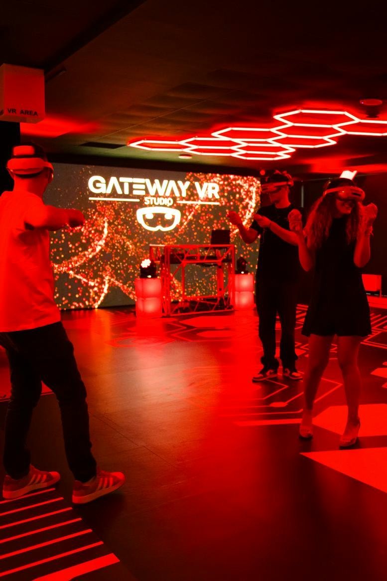 People using virtual reality headsets in a neon-lit gaming room at Cube Center.