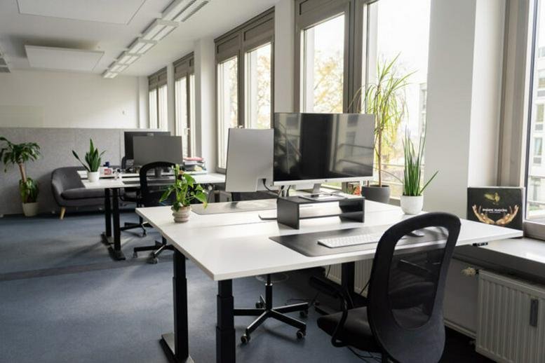 Spacious open-plan coworking area with height-adjustable desks and abundant natural light at 12, Am Brauhaus.