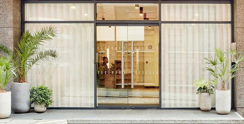 Main entrance of 12, Cock Lane, showing the glass doors and building facade.