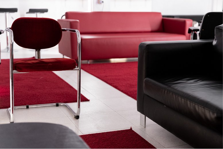 Spacious lounge area featuring a bold red leather sofa and modern black armchairs.
