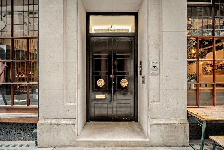 Entrance of the building at 13, Saint Swithin's Lane featuring large black double doors and stone facade.