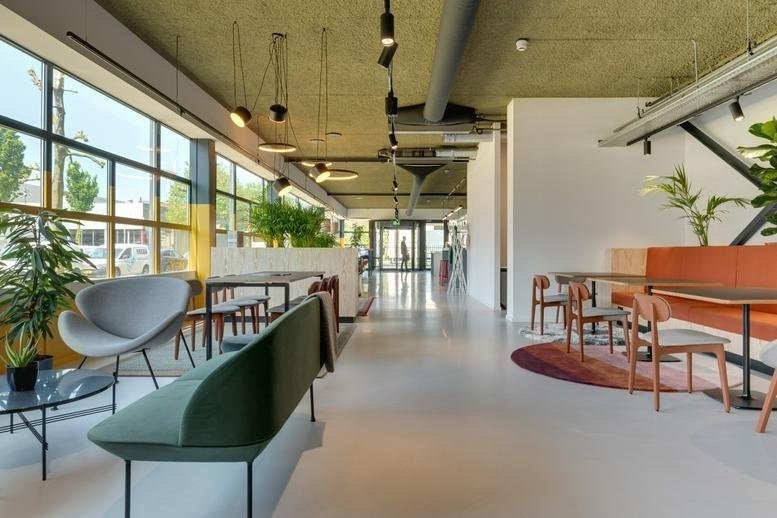 Spacious coworking area at 14, Disketteweg with modern seating and large floor-to-ceiling windows.