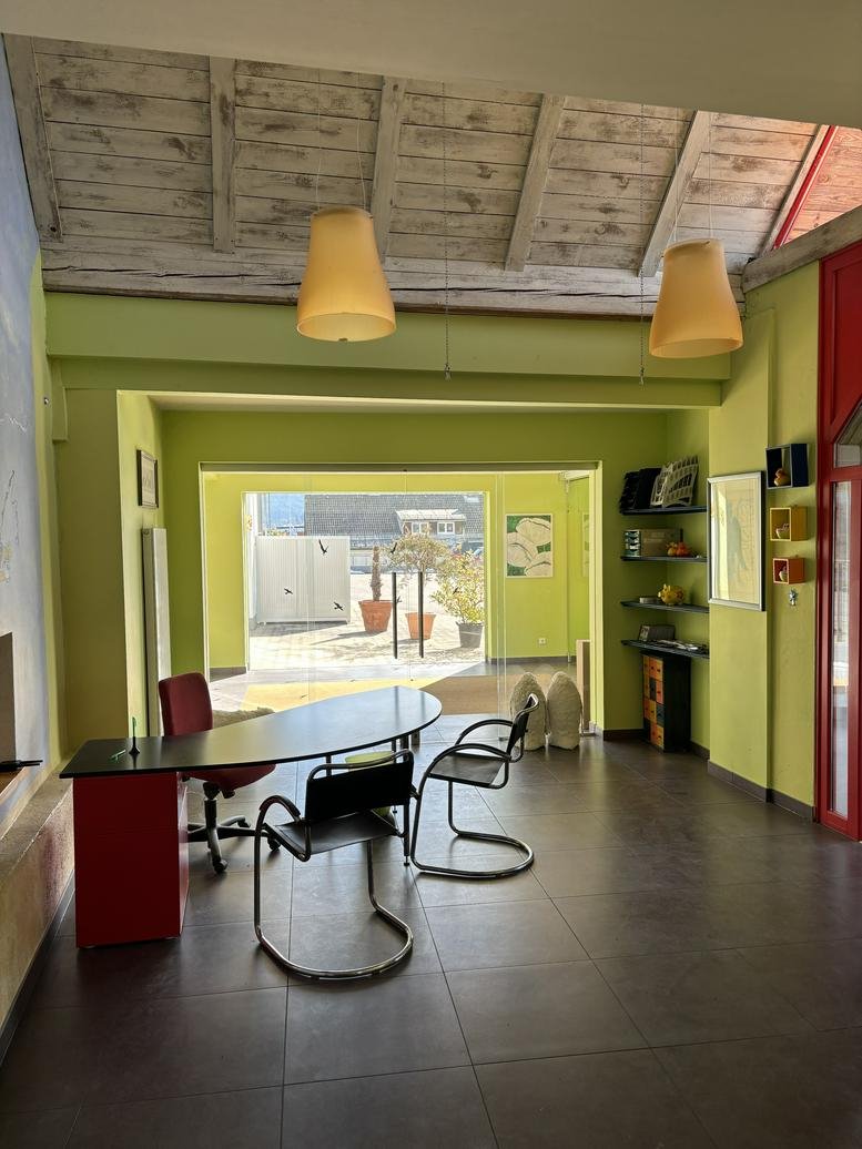 Interior office space at 14, Fasanenweg featuring a curved desk, green walls, and a view to a sunny patio.