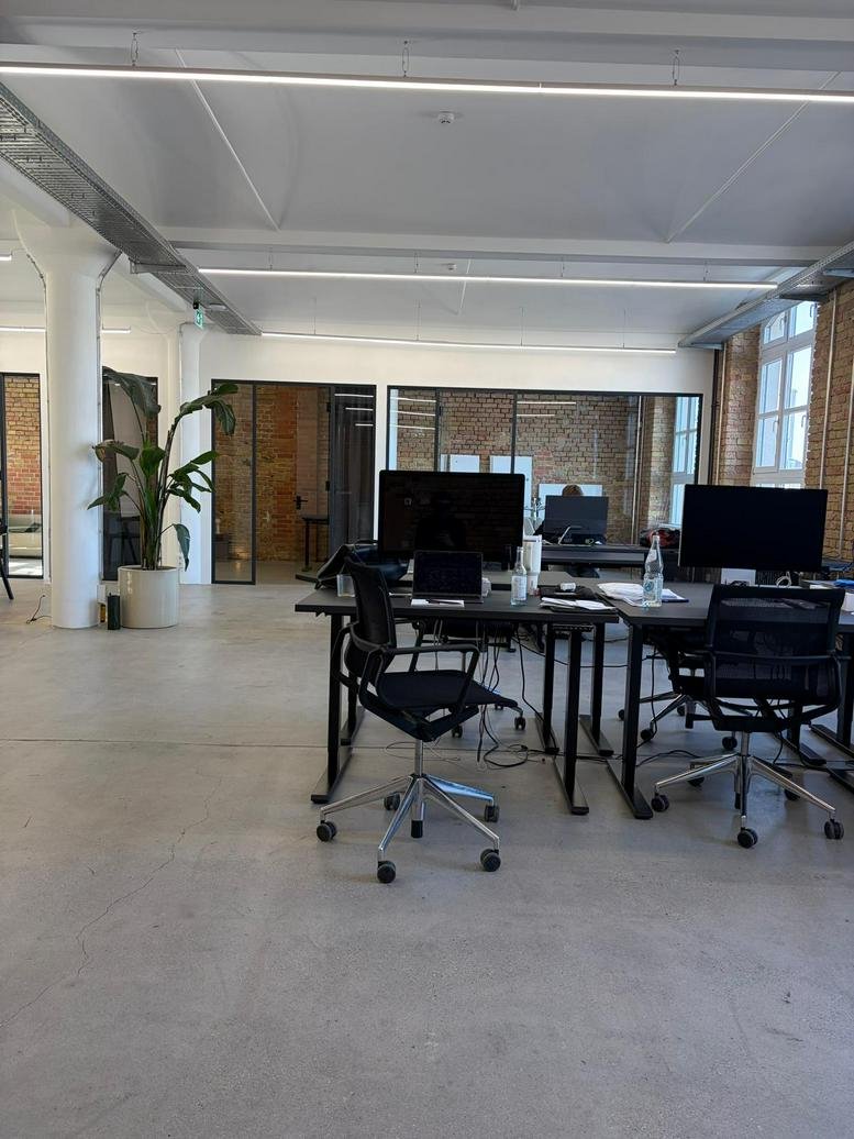 Spacious open-plan workspace at 145, Köpenicker Straße featuring modern desks and potted plants.