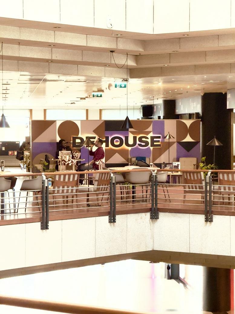 Mezzanine lounge area at Edificio Península Business Center with geometric murals and wooden accents.