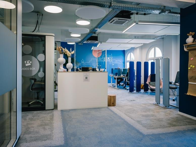 Spacious reception area at 17b, Le Quartier-Hornbach with a white front desk and blue accent walls.