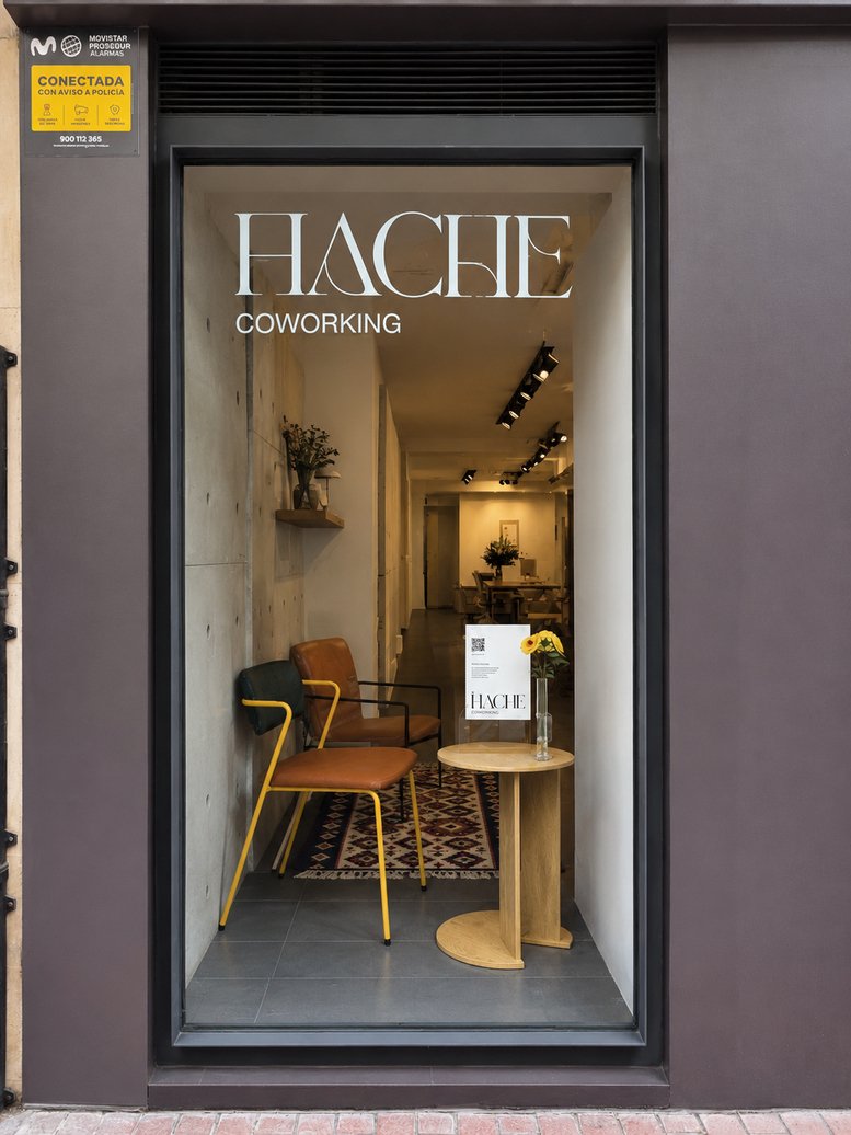 Modern glass entrance of Hache Coworking at 18, Calle Doctores Castroviejo, showing a stylish waiting area.