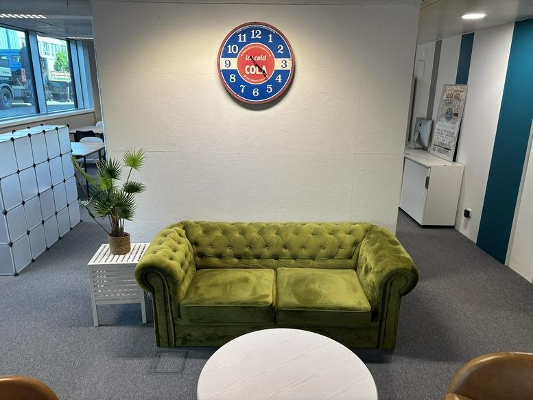 Cozy lounge area with a tufted green velvet sofa and a vintage-style wall clock.
