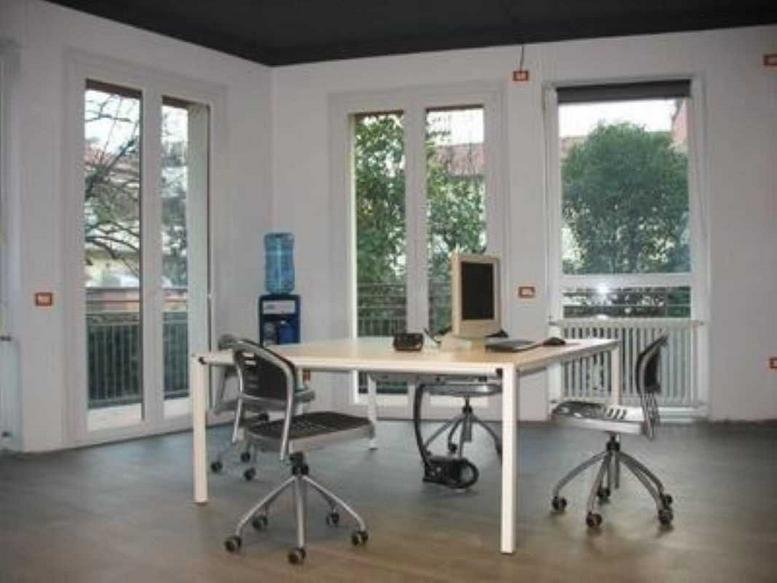 Bright workspace at 18, Via Pietro Giordani, featuring a large white table and tall windows.