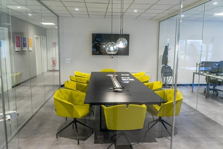 Modern meeting room at 180/a, Via di Tempagnano with yellow chairs and a long black table.