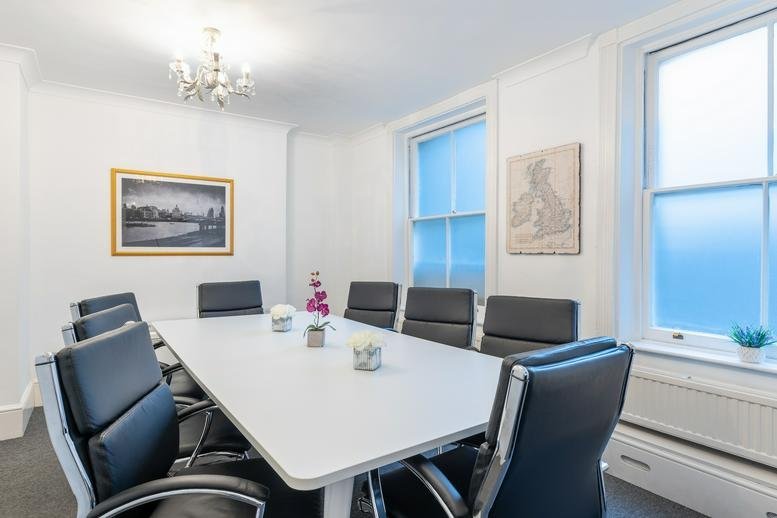 Professional meeting room at 19-21, Christopher Street featuring a large white table and black leather chairs.