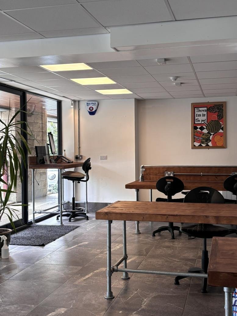 Spacious communal area at Oldgate House featuring heavy timber tables and industrial-style furniture.