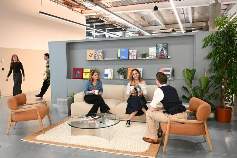 Lounge area with a modern sofa, coffee table, and bookshelves at 191 Wood Lane MediaWorks.