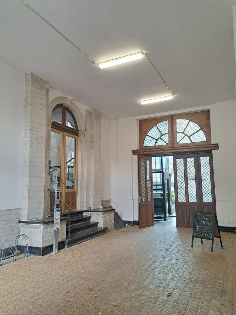 Bright entrance hall with large wooden doors and a chalkboard sign.