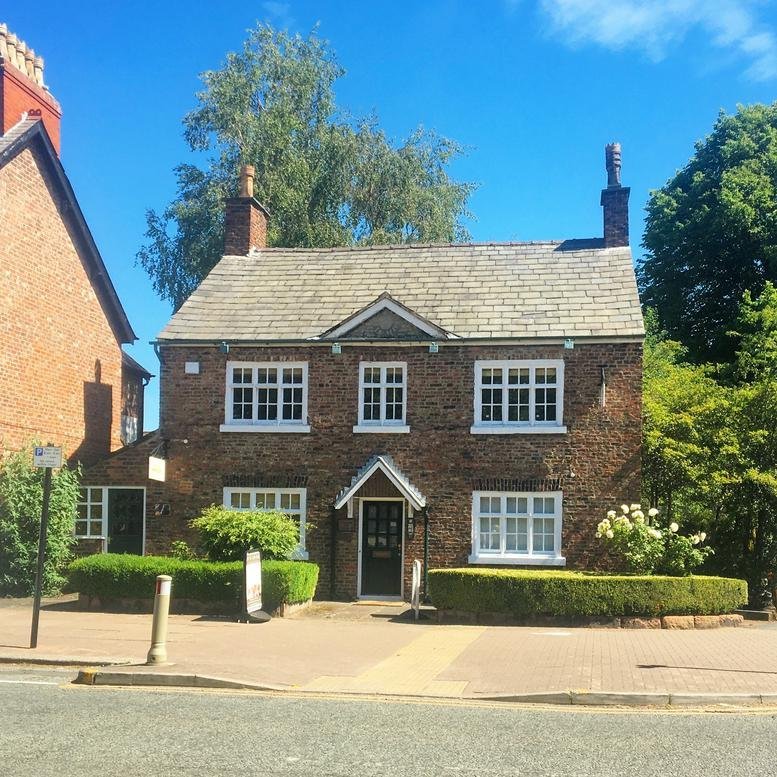 Exterior view of the historic brick building at 209-211, Ashley Road, featuring white sash windows.