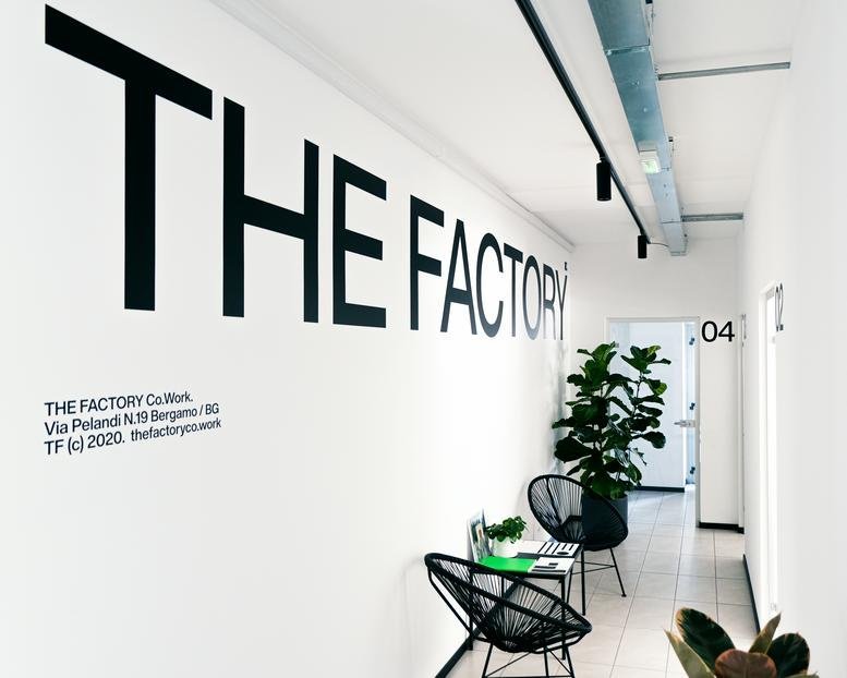 Bright lobby with bold branding at THE FACTORY Co.Work, 21 Via Luigi Pelandi.