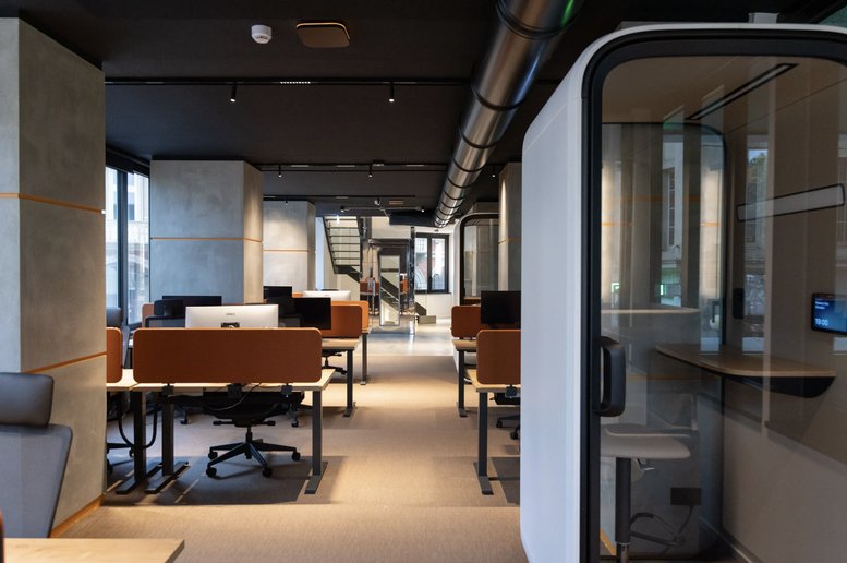 Spacious open-plan workspace at 21, Via Pietro Micca with modern desks and a private soundproof phone booth.