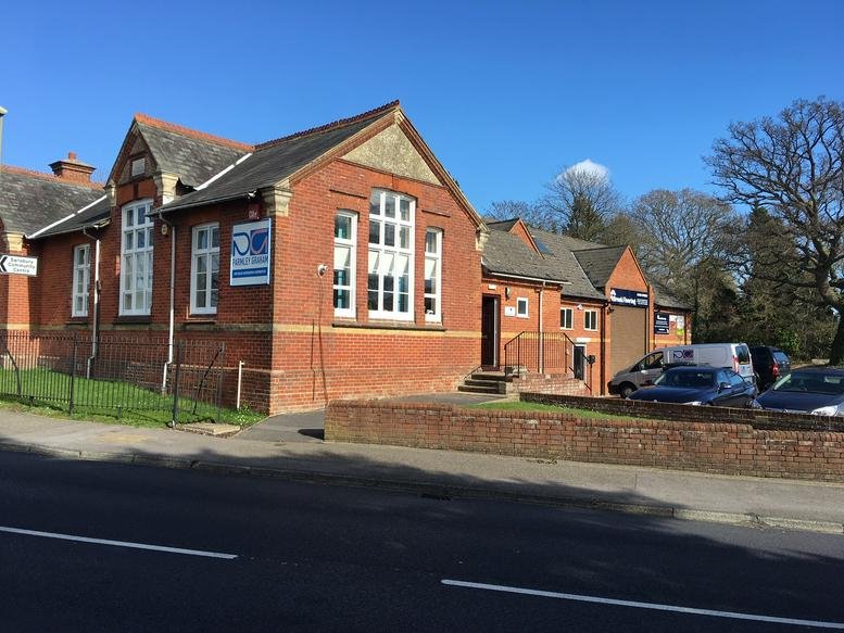 Exterior view of the red brick building at 216 Barnes Lane with large arched windows and clear blue sky.