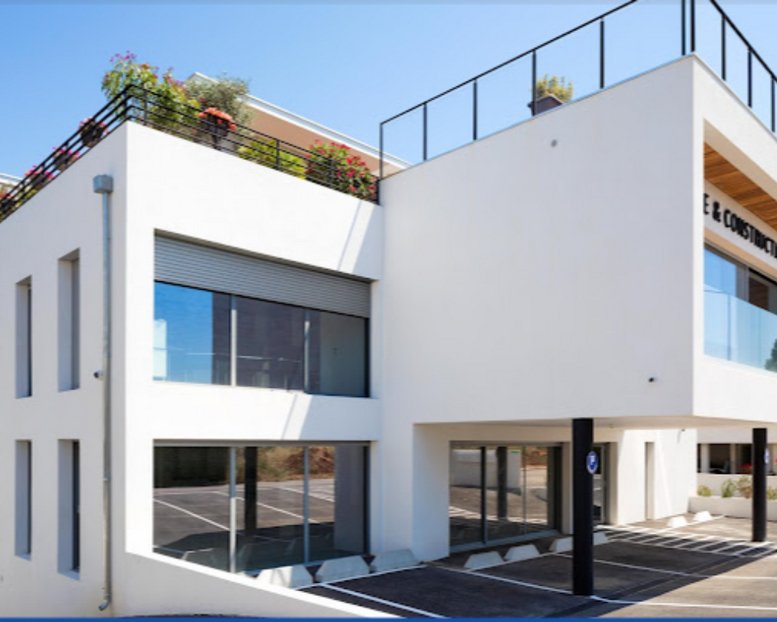 Exterior view of the modern white office building at 2390, Route des Milles with a rooftop garden.