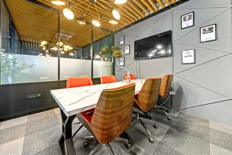 Meeting room at 24, Fairley Street with a white marble table, orange chairs, and a slatted wood ceiling.