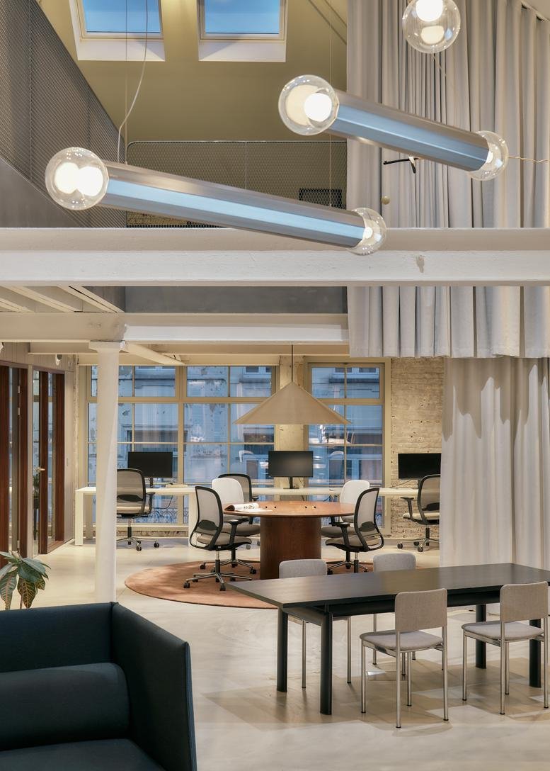 Spacious office with multiple work areas and large pendant lights.