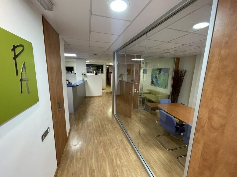 Bright glass-walled reception and corridor at 25, Carrer de Solà, Bajos.