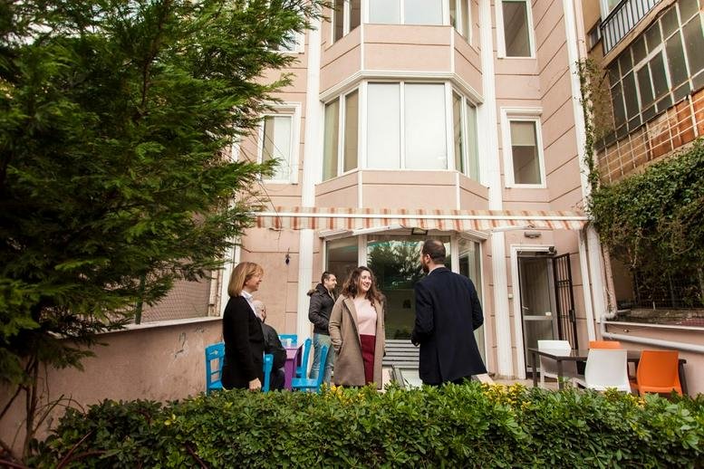 Exterior view of the peach-colored building facade at 3 / 1, İstasyon Yolu Sokağı with a garden patio.