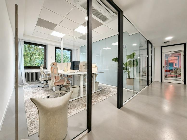 Spacious open-plan office at 32, Blaubach featuring glass walls and ergonomic seating.
