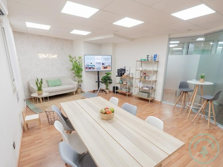 Spacious communal lounge and meeting area at 32, Carrer de Foix,1-6 with light wood floors and potted plants.