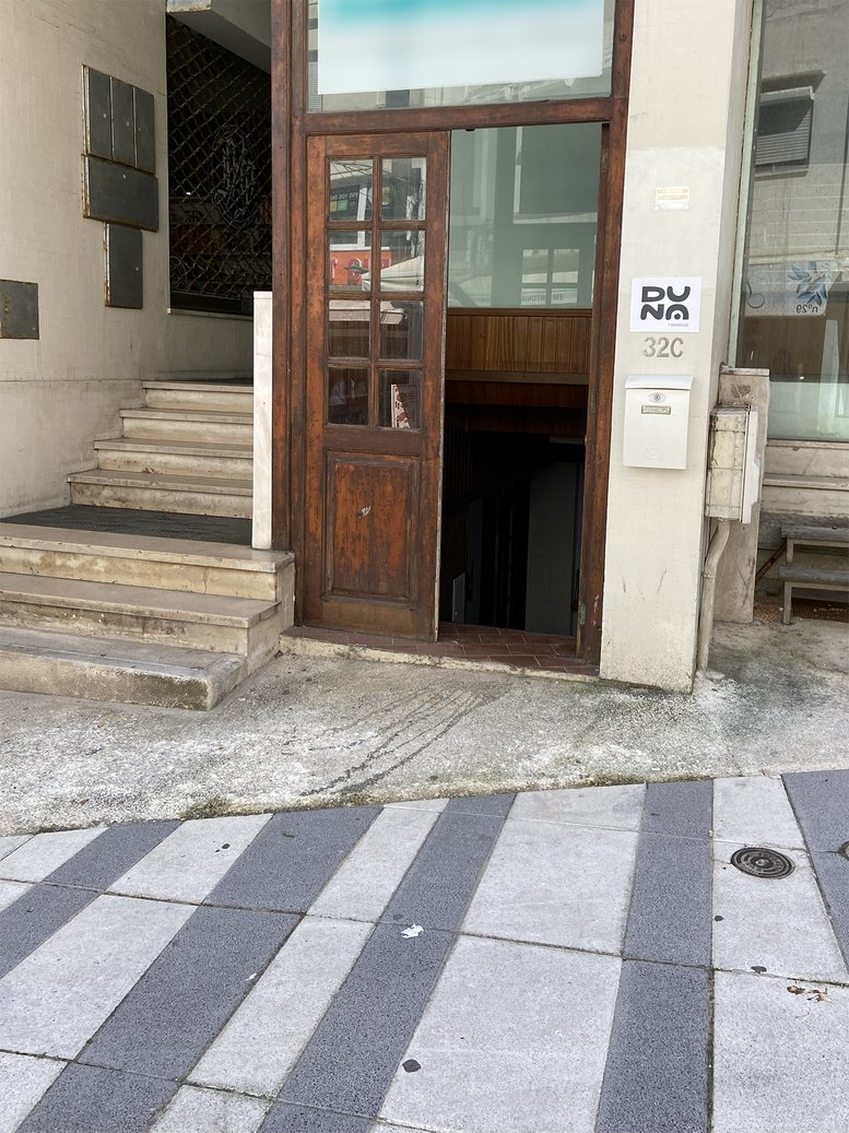 Exterior entrance of 32C, Rua dos Pescadores, showing a wooden door and marble stairs.