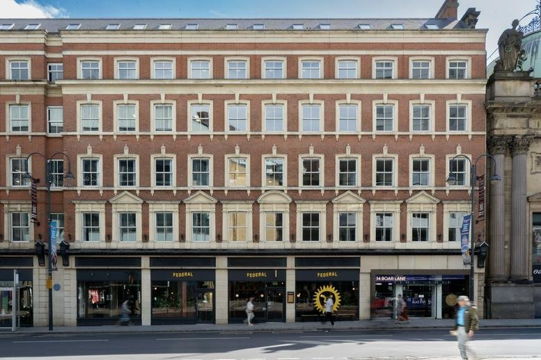 Grand brick and stone exterior of 34 Boar Lane with large shopfront windows at street level.