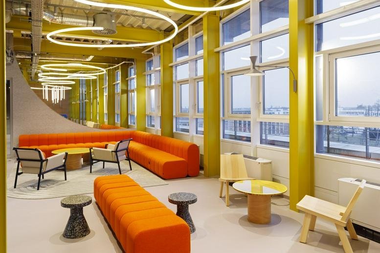 Modern communal lounge at 34, Lilienthalallee featuring orange sofas and circular yellow ceiling lights.