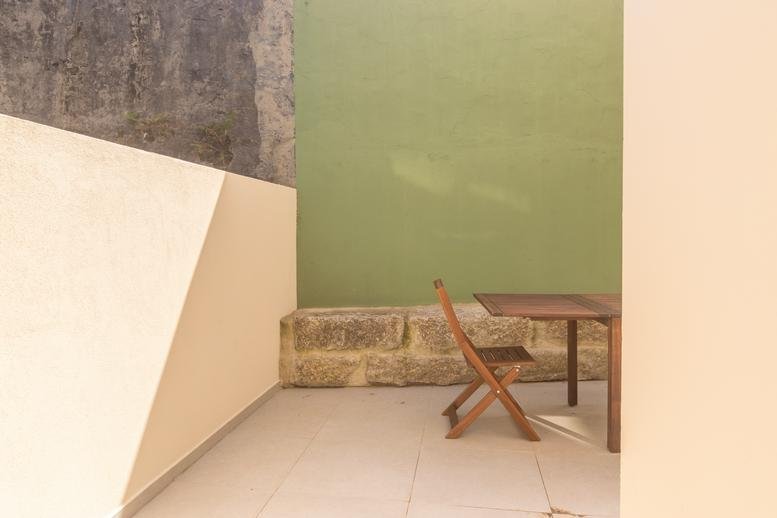 Close-up of an outdoor wooden chair and table on a stone-walled patio.