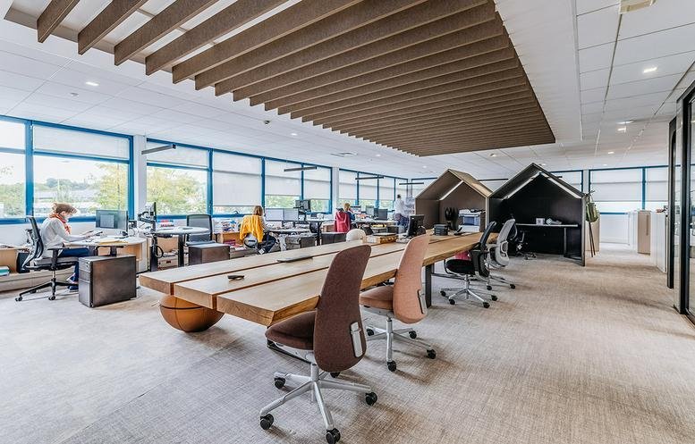 Open-plan office at 345, Greenacres Road featuring a long wooden communal desk and creative house-shaped work pods.