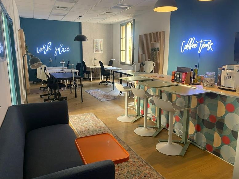 Spacious communal coworking lounge at 39, Cours de la République featuring neon signs and a bar area.