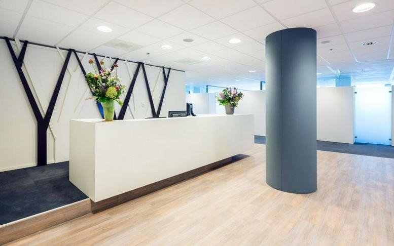 Modern white reception desk at 3rd Floor Viñoly Tower with a sculptural black wall design and green plants.