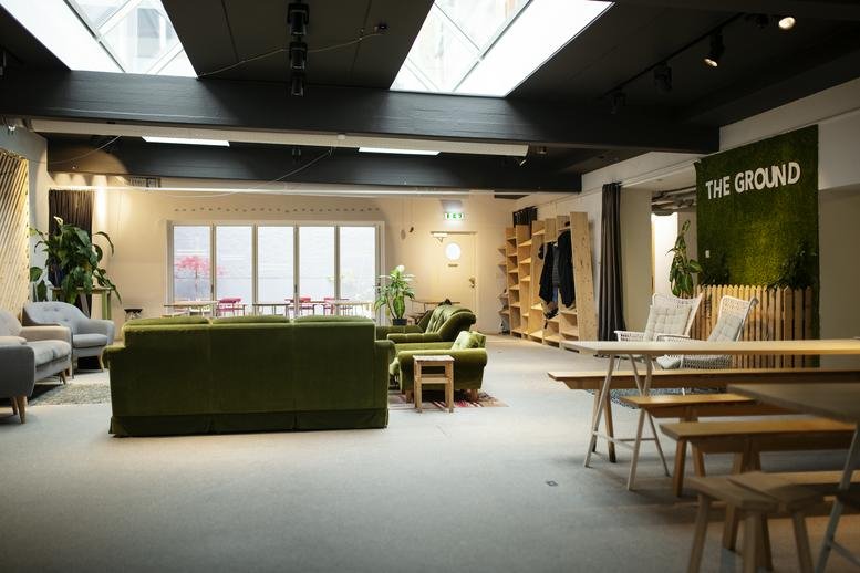 Spacious common area at 4, Bredgatan with green velvet sofas and natural light from large skylights.