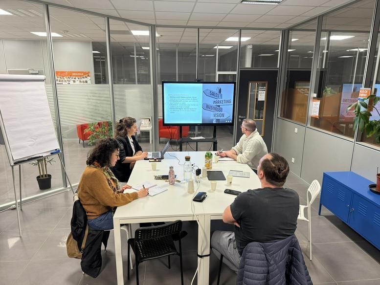 Group meeting in a glass-walled office with a large screen presentation.