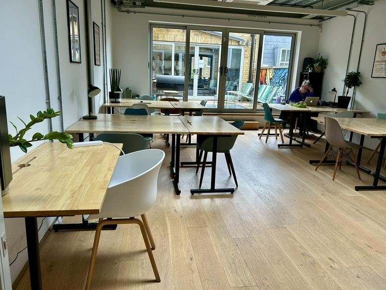 Spacious workspace at 41, Pitfield Street with light wood desks and large glass doors leading outside.