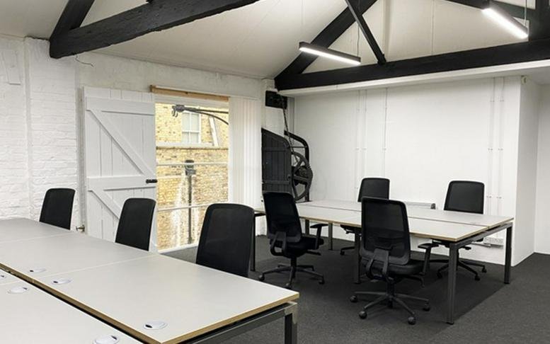 Modern meeting room with a large table and black chairs set against white walls.