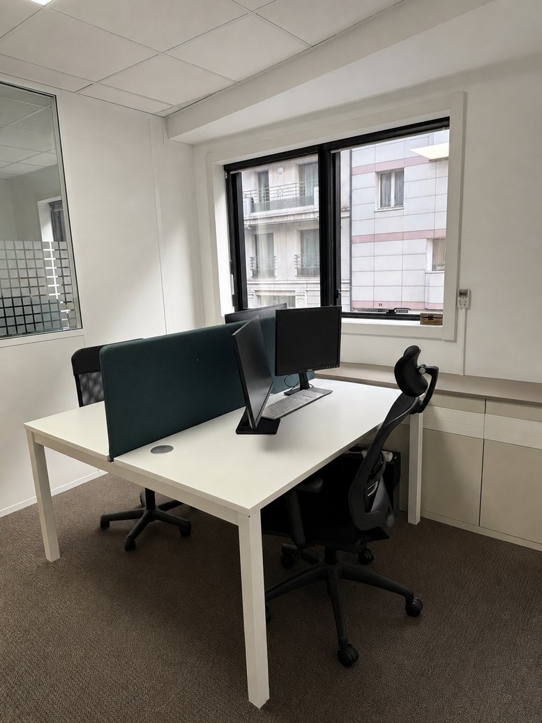 Workspace at 48, Rue Victor Hugo featuring dual desks with privacy screens and ergonomic chairs.