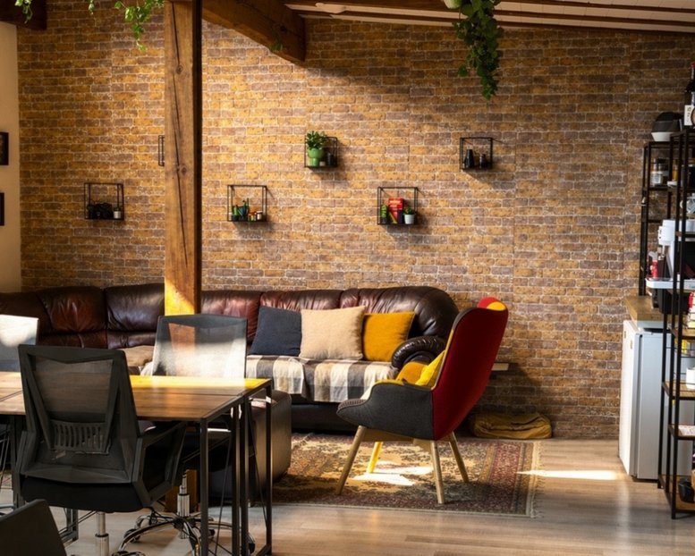 Spacious coworking area at 49, bulevard Vasil Aprilov with leather sofas and exposed brick walls.