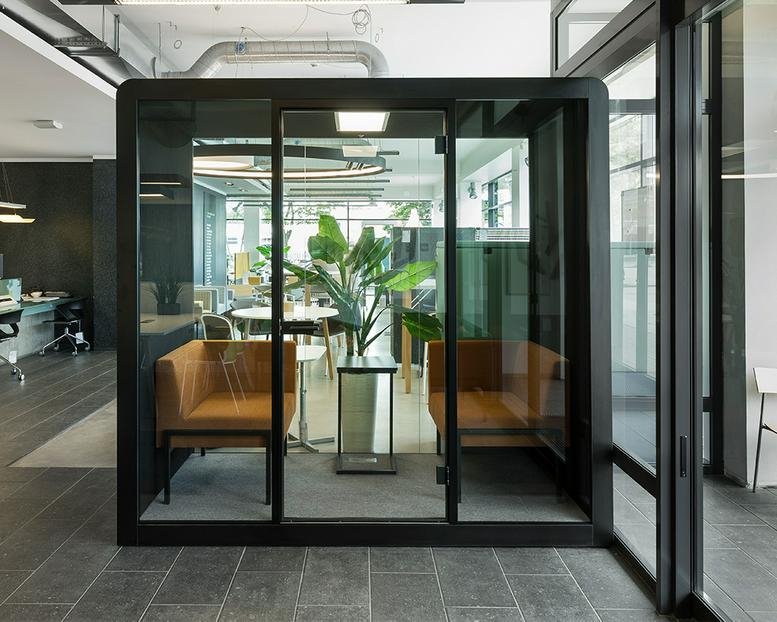 A modern glass meeting pod with comfortable brown seating at 49, Kingsland Road.