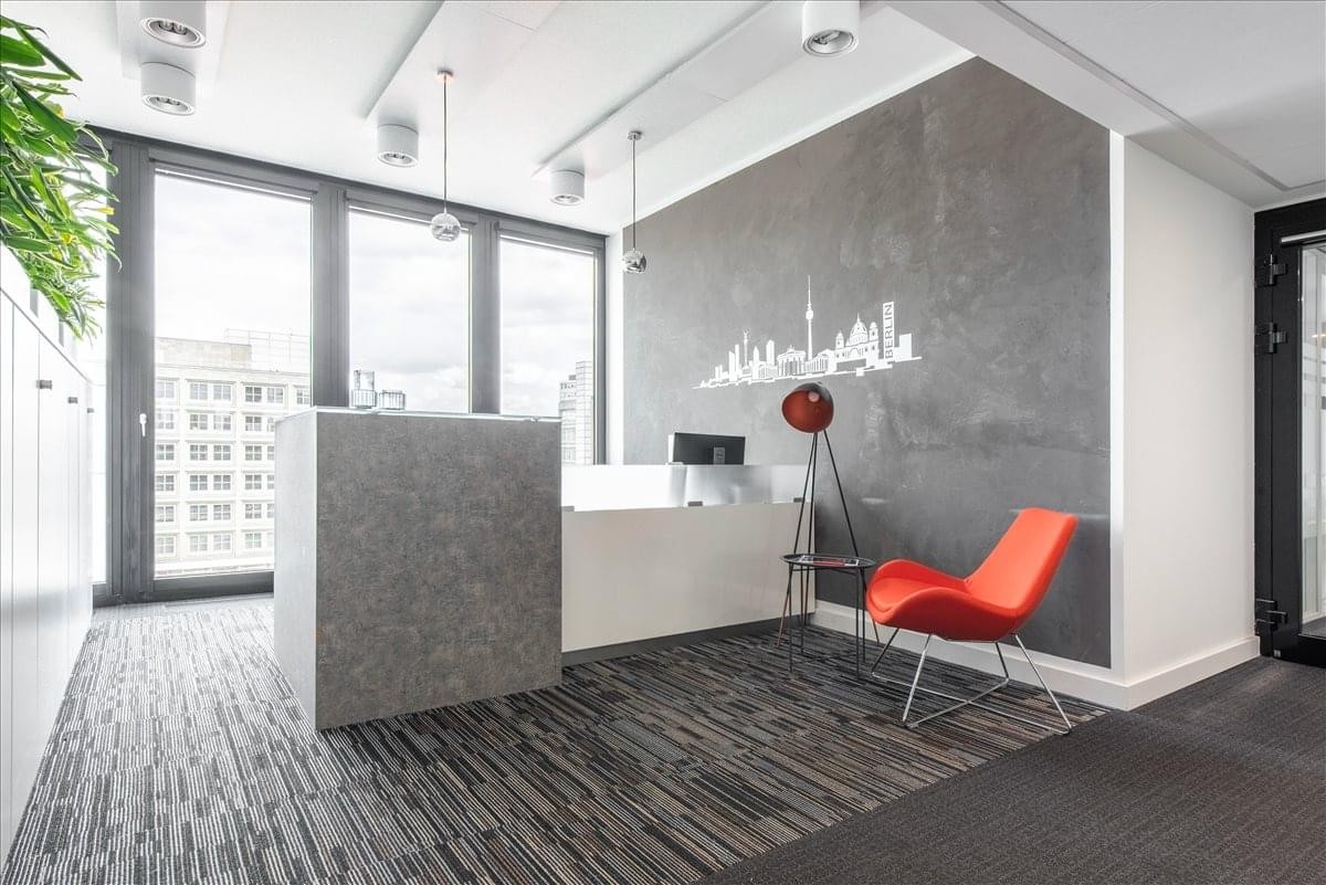 Reception area with a textured stone desk, city skyline wall decal, and a vibrant red accent chair.