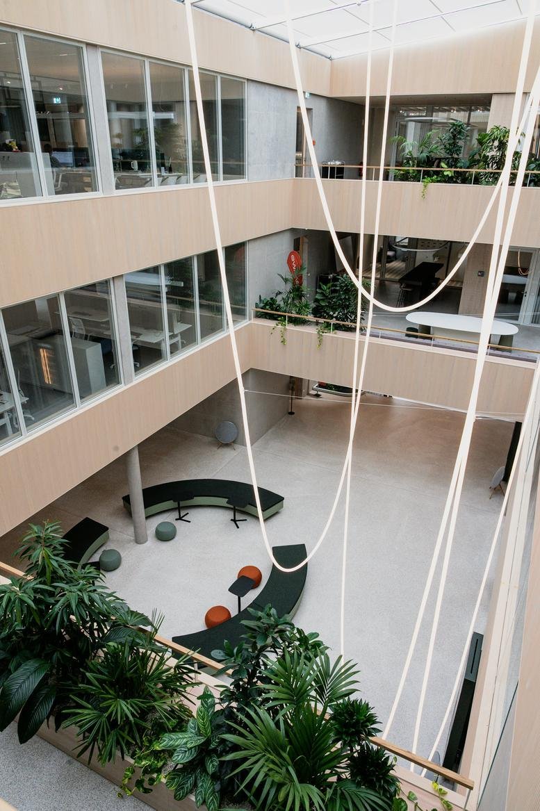Spacious three-story atrium with hanging lights and indoor greenery at 5, Im Nasswasen.