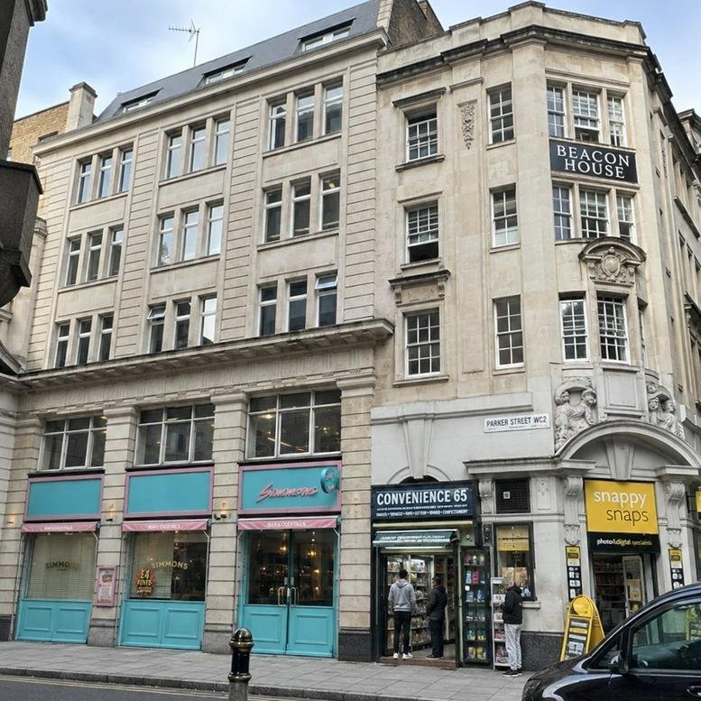 Grand stone exterior facade of Beacon House at 53, Parker Street with ground floor retail units.