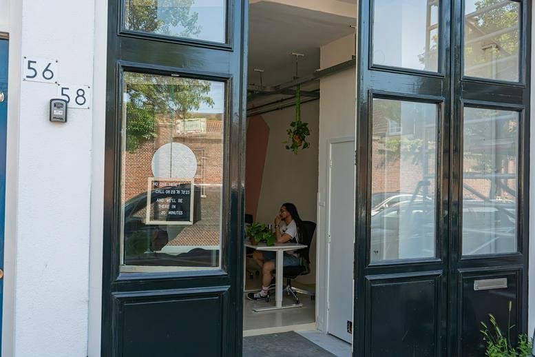 Exterior entrance of 58, Lange Beestenmarkt featuring large black industrial glass doors and street numbering.
