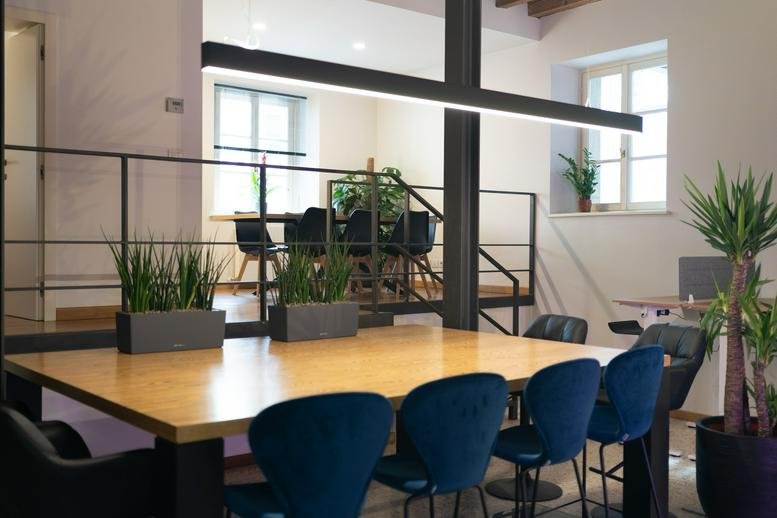 Coworking area with a large communal table and a mezzanine level in the background.