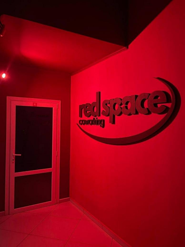 Backlit corporate logo for Red Space Coworking on a deep red wall.