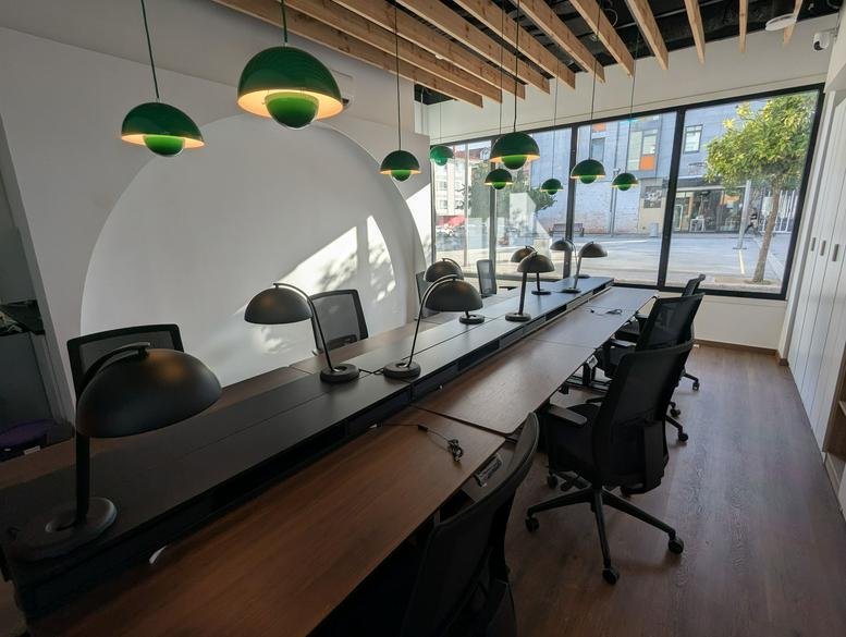 Spacious open-plan workspace at 6, Plaza Horta de Abaixo with wooden ceilings and green pendant lights.